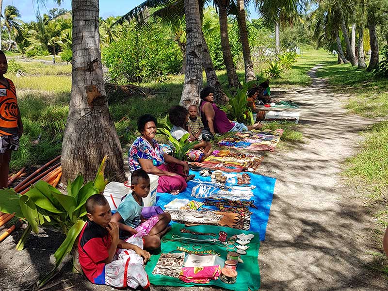 Kvinnor och barn säljer hantverk i den lokala byn